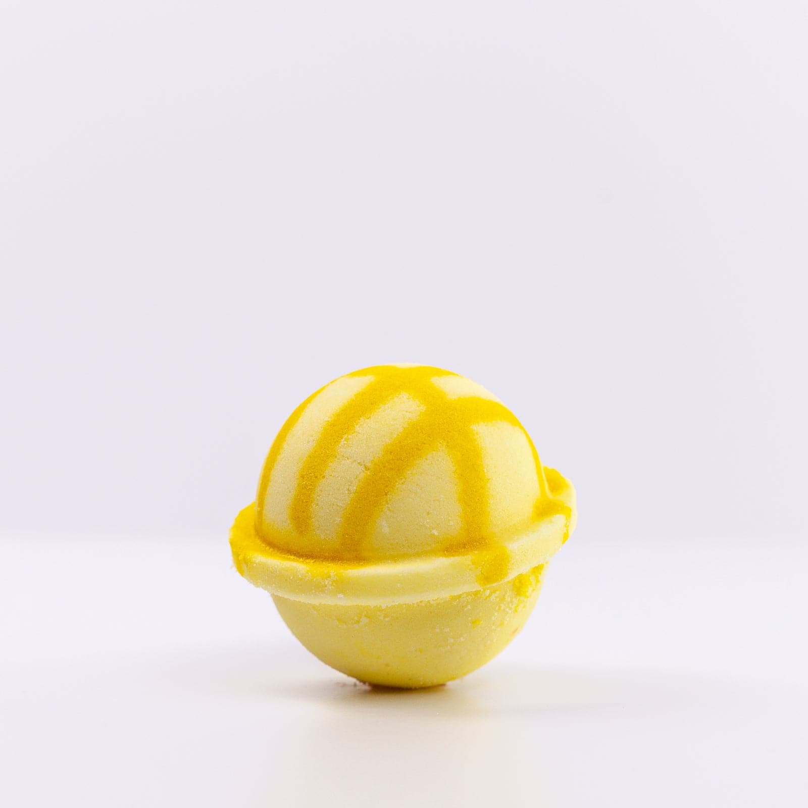 Light yellow Bath Bomb with dark yellow design against white background 