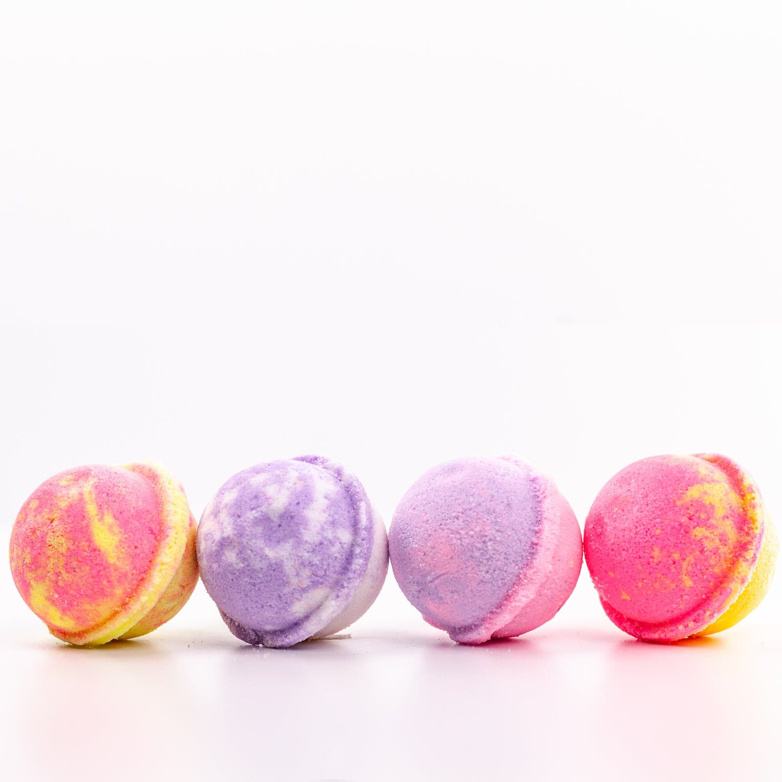 4 multi colored Mini Bath Bombs placed in a row