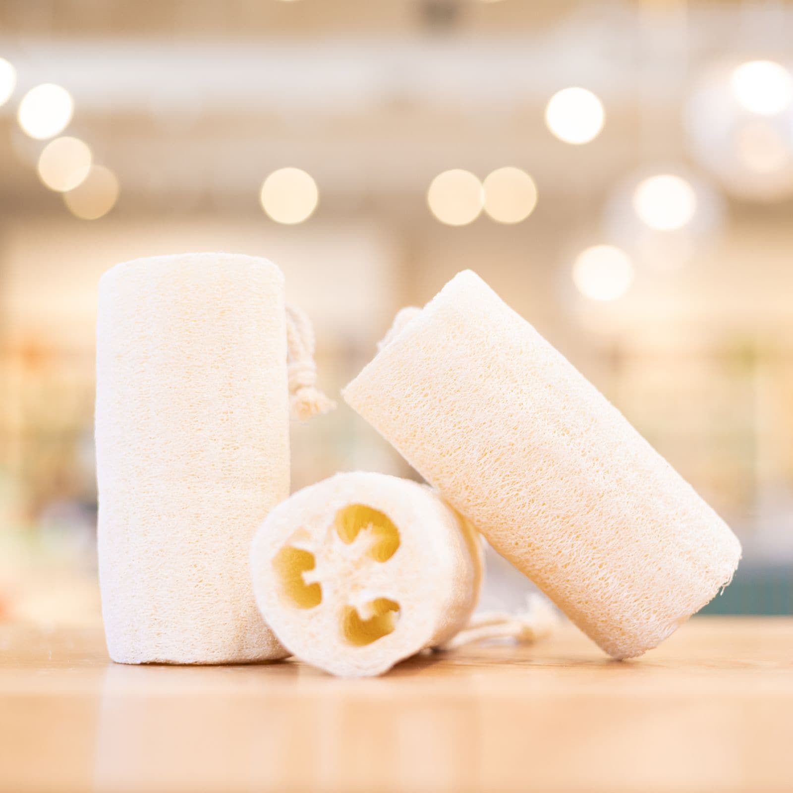 Three natural colored loofahs arranged on wooden counter